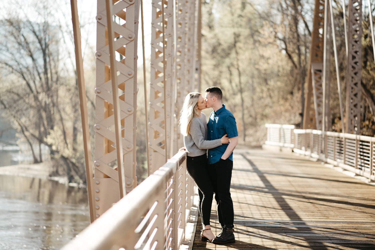 engaged happy couple kissing on bridge