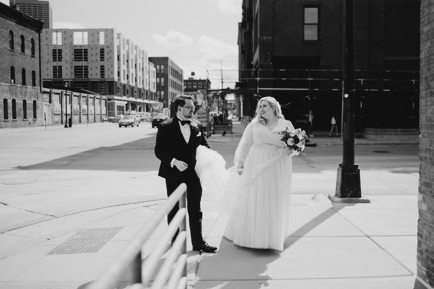 Black and white image of bride and groom walking around Downtown Minneapolis