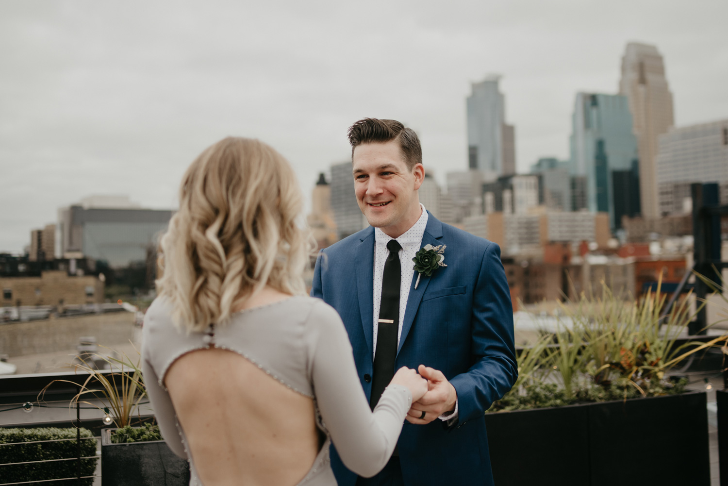 Groom seeing bride first look blue suit downtown Minneapolis rooftop