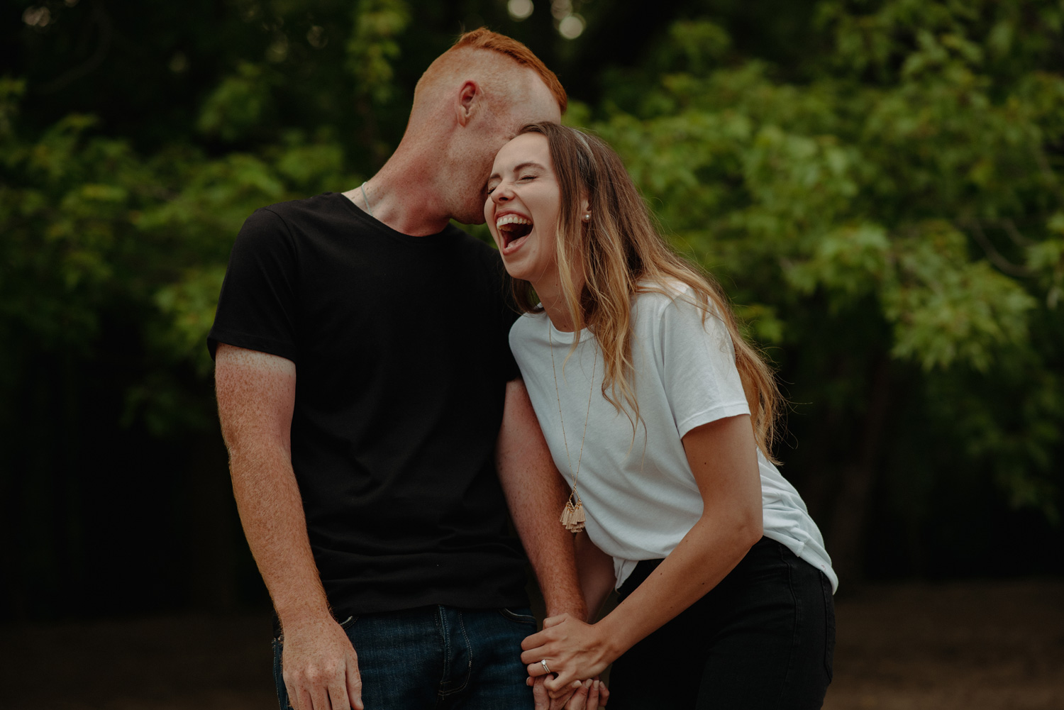Couple holding hands and laughing minnehaha river engagement photos