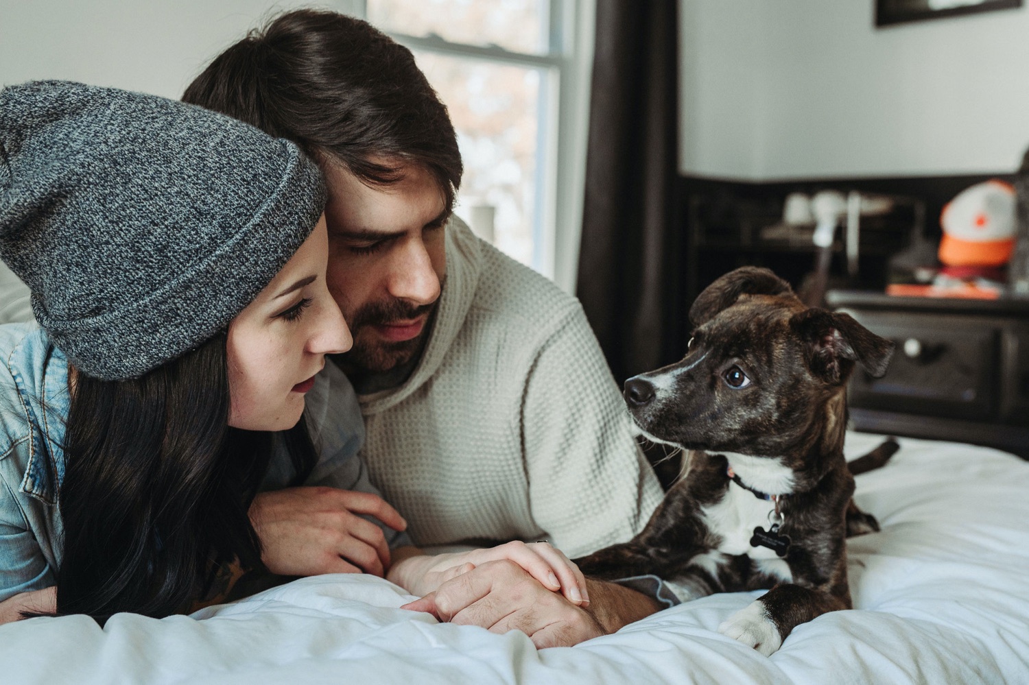couple cuddling on in bed in home session with dog
