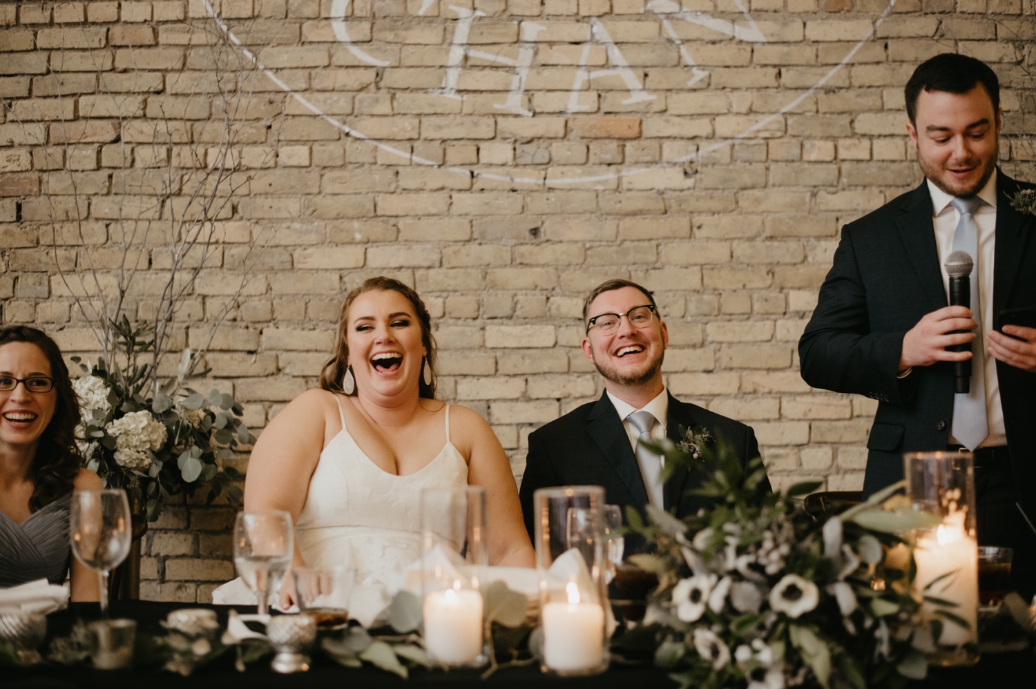 bride and groom laughing during toasts lumber exchange minneapolis wedding