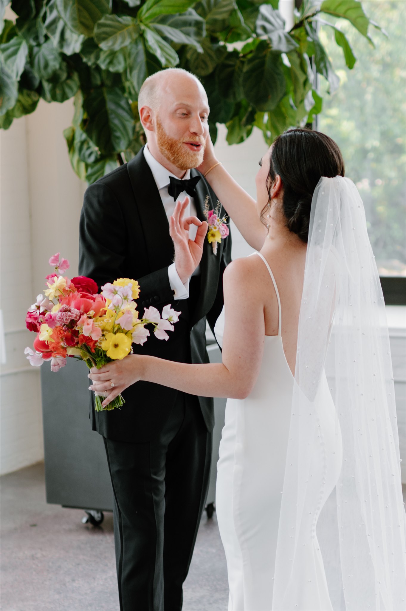 Groom gives a thumbs up to bride while she holds a bouquet