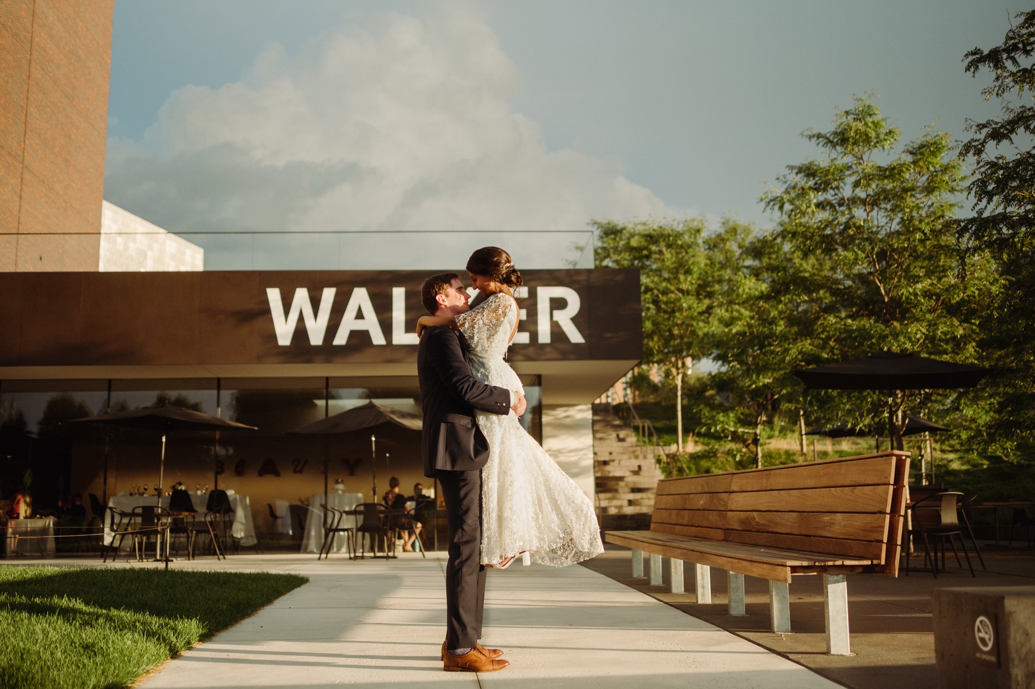 Groom holding up bride and kissing outside on sidewalk walker art center wedding
