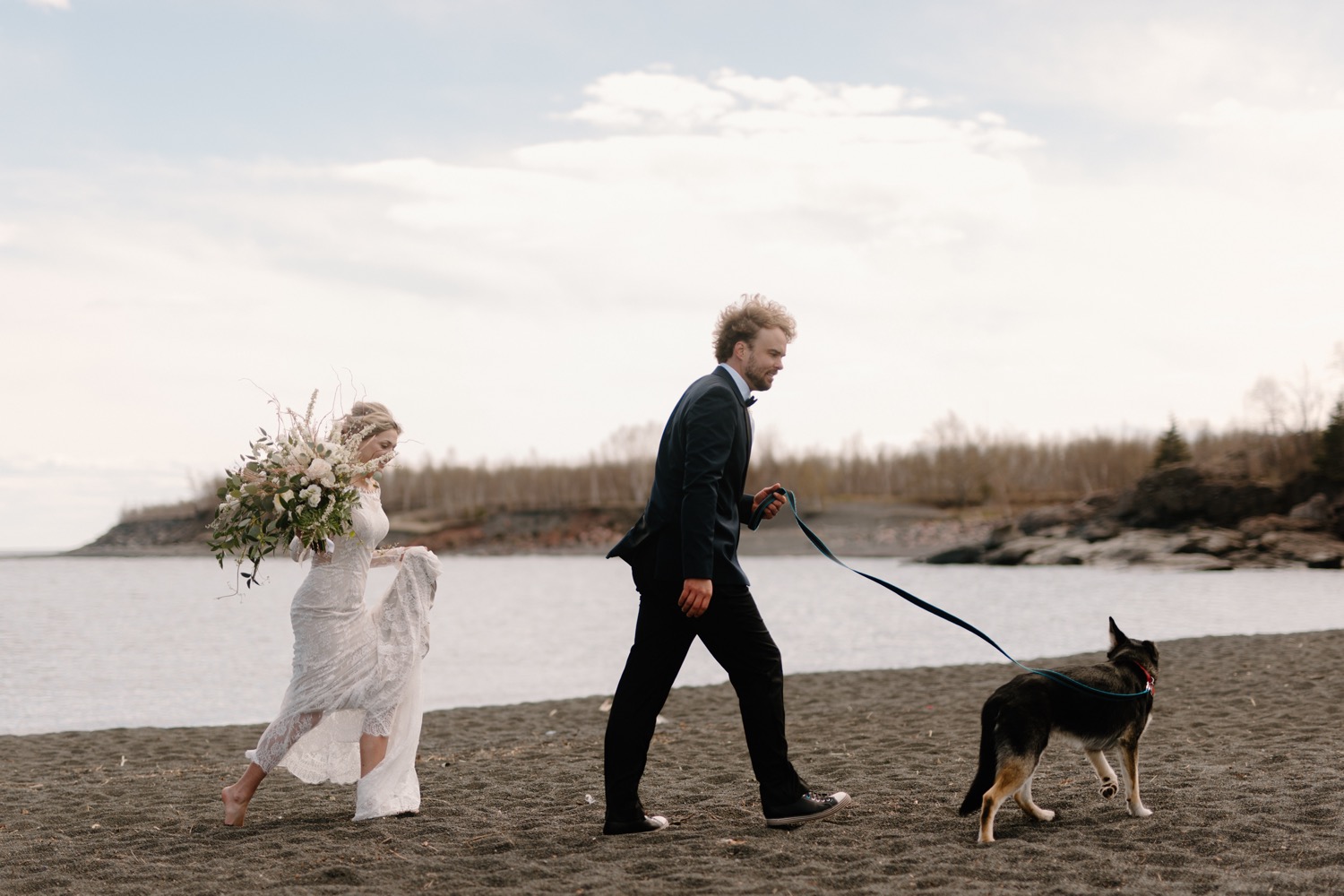 bride and groom walking on beach with dog