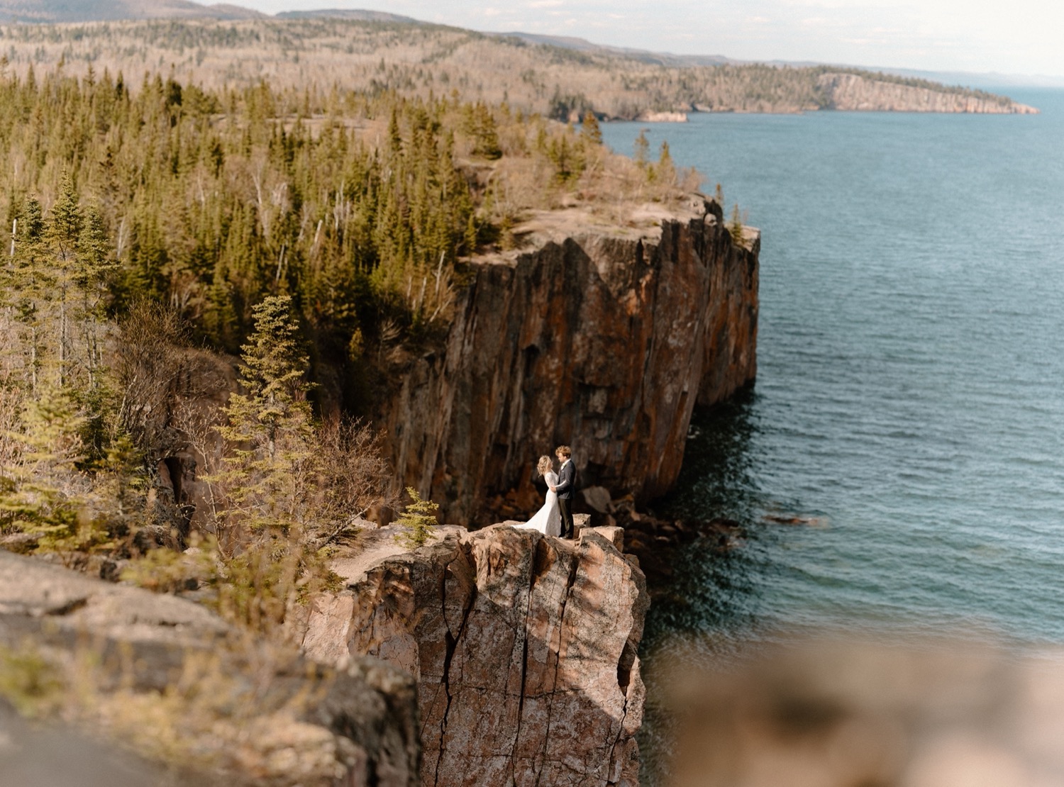 bride and groom standing on a cliff outdoors in northern minnesota